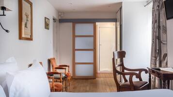 Une chambre d’hôtel comprenant un lit, un bureau, une chaise, une bibliothèque et une porte donnant sur une autre pièce.