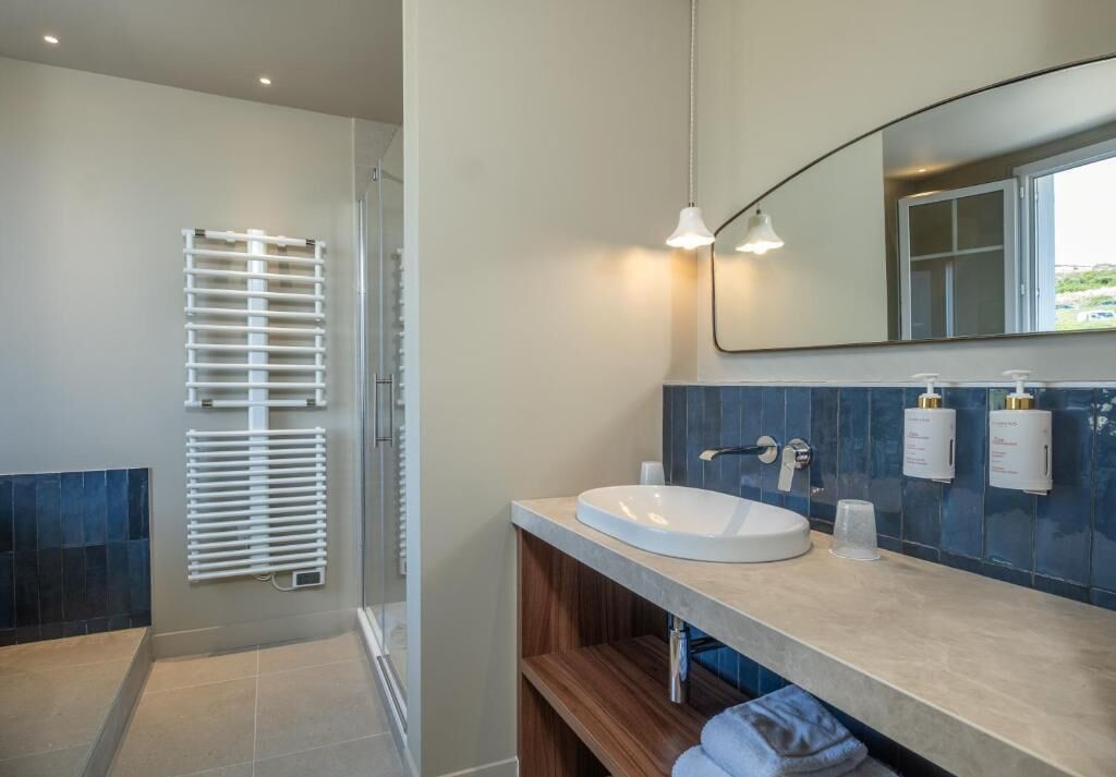 Un baño moderno con un lavamanos blanco, un espejo y un perchero para toallas.