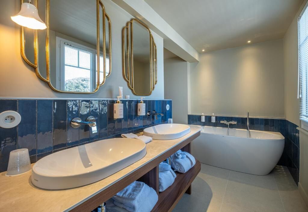 Une salle de bain moderne avec deux lavabos, une baignoire et un meuble-lavabo avec des serviettes.