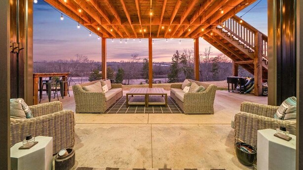 Un espacio de estar al aire libre con mobiliario de mimbre y techo de madera, con vistas a un paisaje pintoresco.