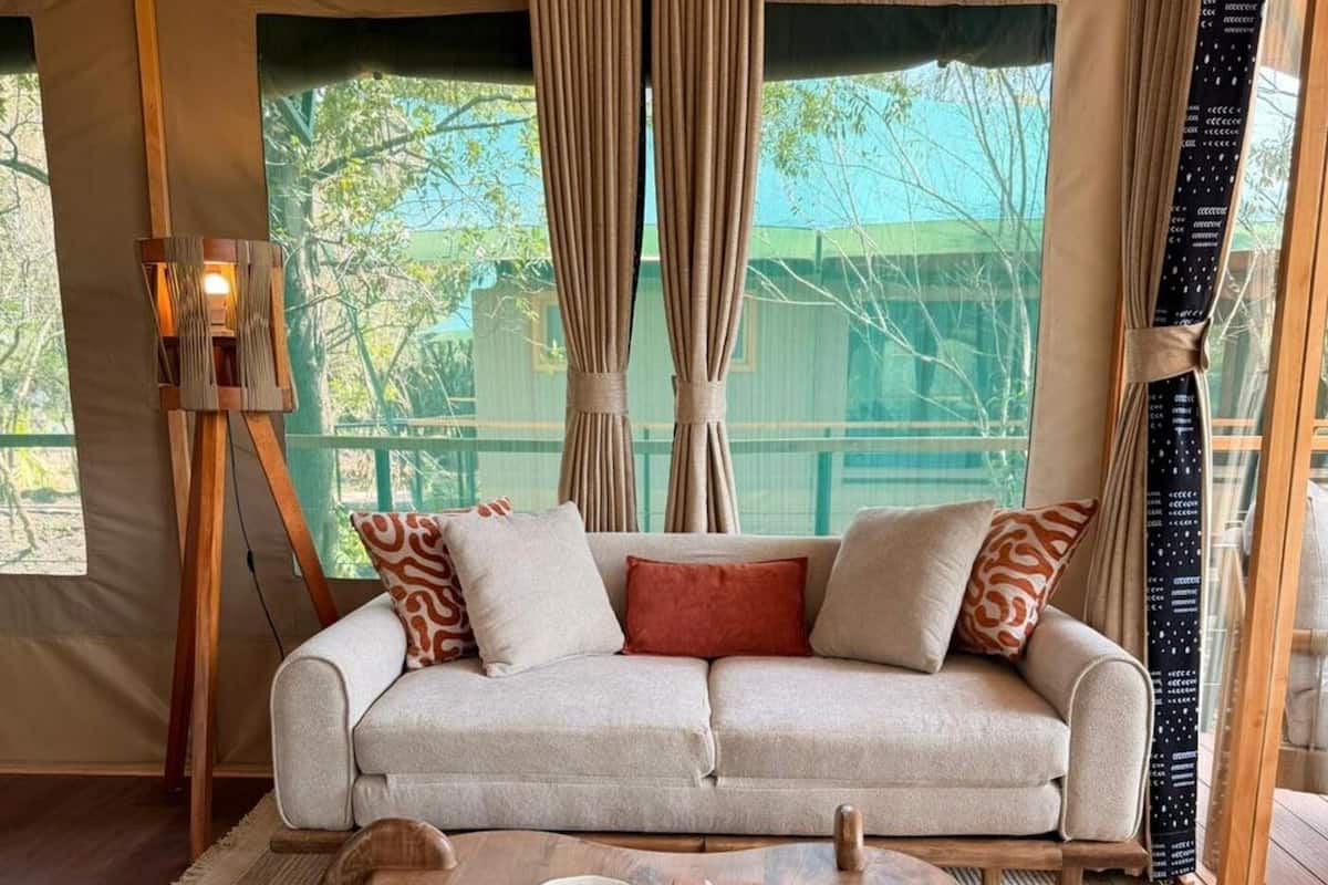 Una habitación acogedora con un sofá, una mesa de centro de madera y un cuadro sobre un atril.