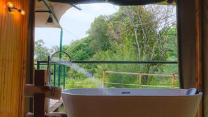 Una bañera con vista a un bosque a través de una ventana.