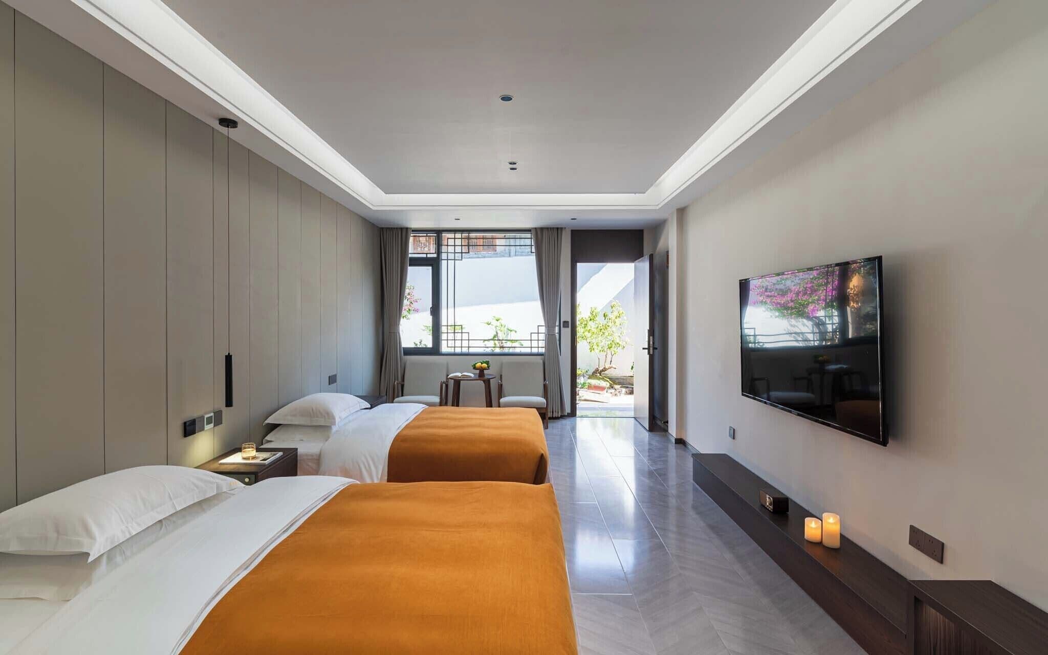 Een hotelkamer met twee bedden, een televisie, een tafeltje en uitzicht op buiten.