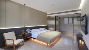 Een moderne slaapkamer met een bed, nachtkastje, stoel en een grote spiegel.
