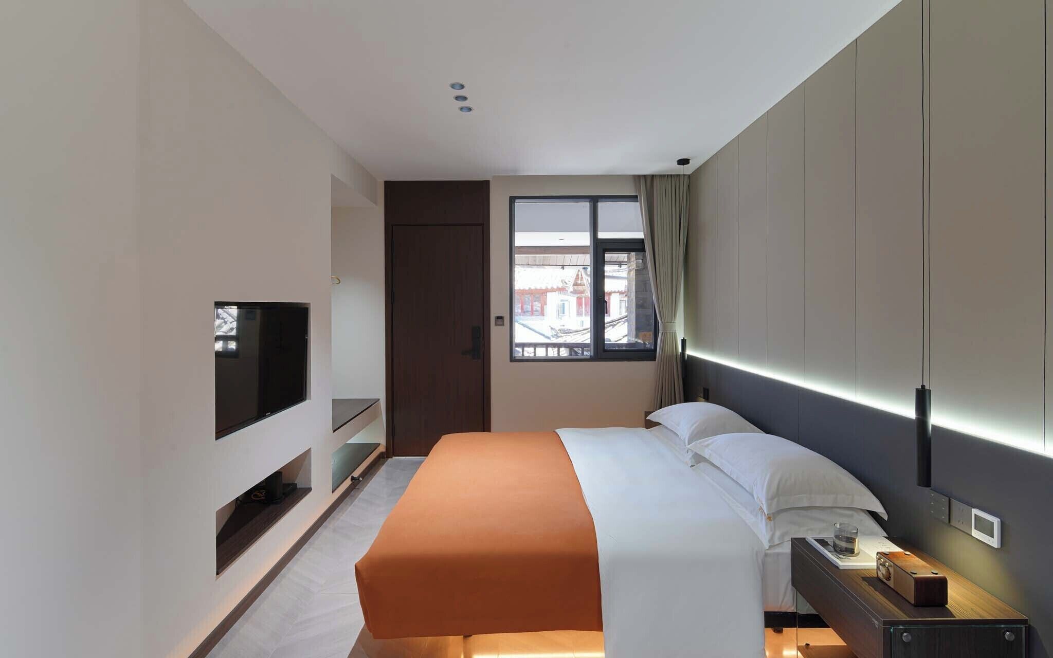 Een hotelkamer met een bed, een televisie, een raam en een nachtkastje.