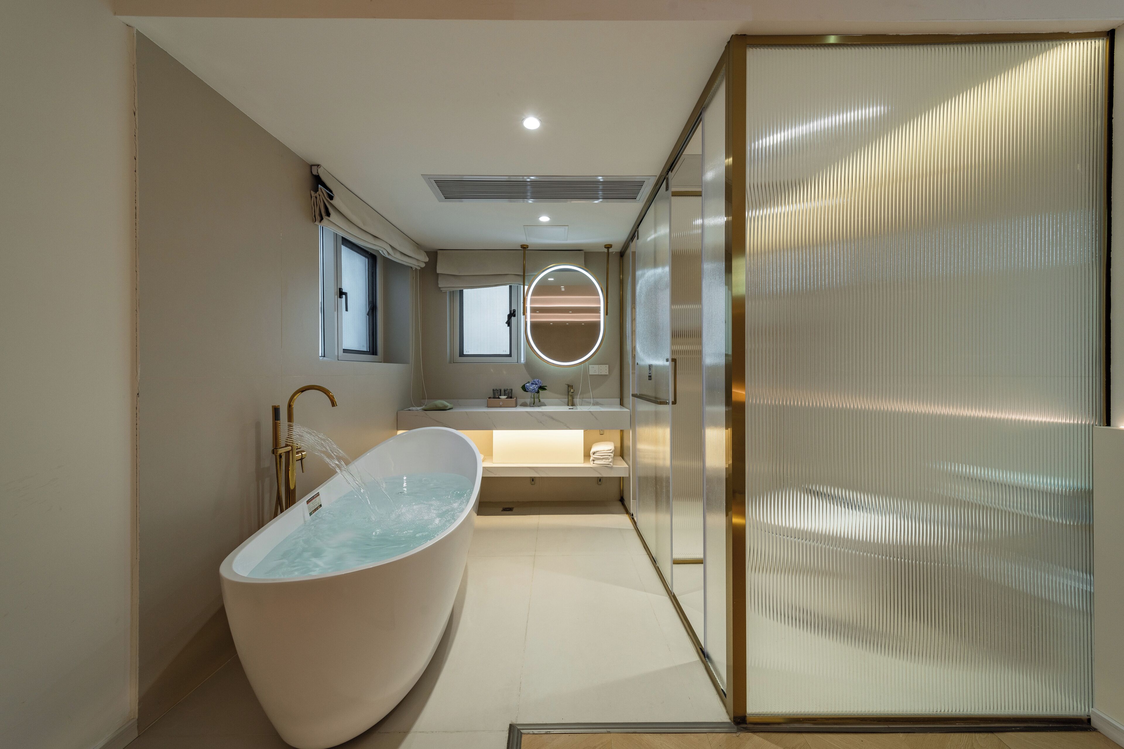 A modern bathroom with a freestanding bathtub, a vanity with a mirror, and a walk-in shower.