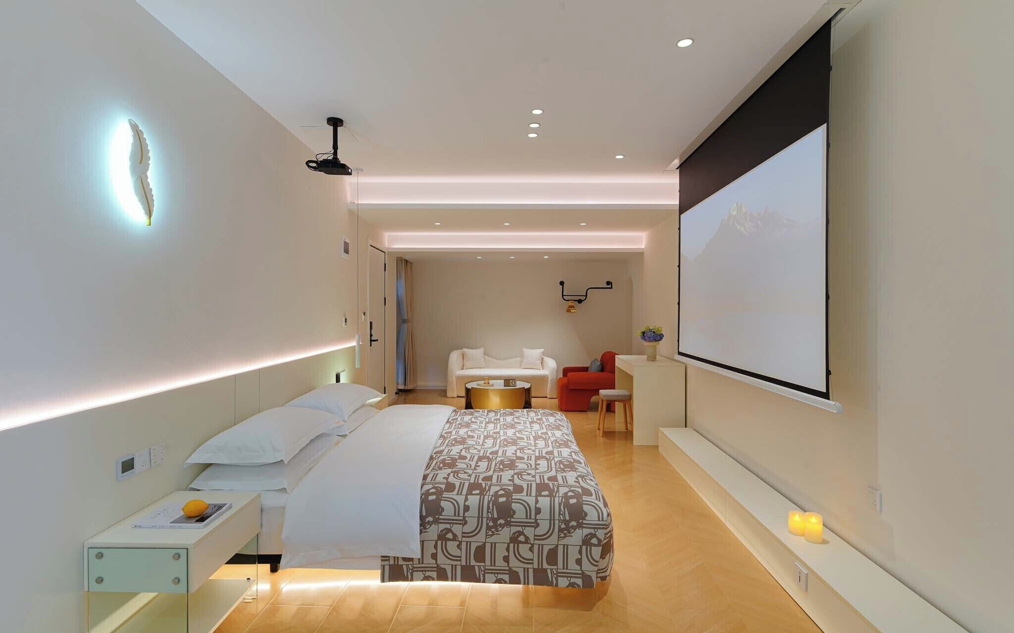 Een moderne hotelkamer met een bed, nachtkastje en een groot scherm.