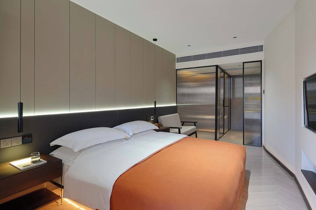 Una habitación de hotel moderna con cama, mesita de noche, silla y televisor.