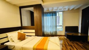 A hotel room with a bed, a round table, and a window with curtains. - Hotel Dhaka Express (Kathmandu)