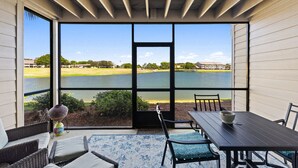 A covered patio with a view of a lake, outdoor furniture, and a table. - Barefoot Bliss | Lakefront Villa Steps from Miramar Beach (Miramar Beach)