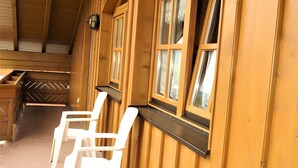 Un interior de madera con una ventana, una silla blanca y un banco de madera.