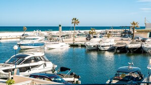 A marina with boats docked, a clear sky, and a calm sea.
