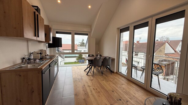 Una cocina moderna con comedor, ventanas amplias y vistas al vecindario.