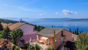 A coastal building with a balcony, a view of the sea, and a mountainous background. - Apartment in Dramalj with balcony, sea view and pool (Crikvenica)