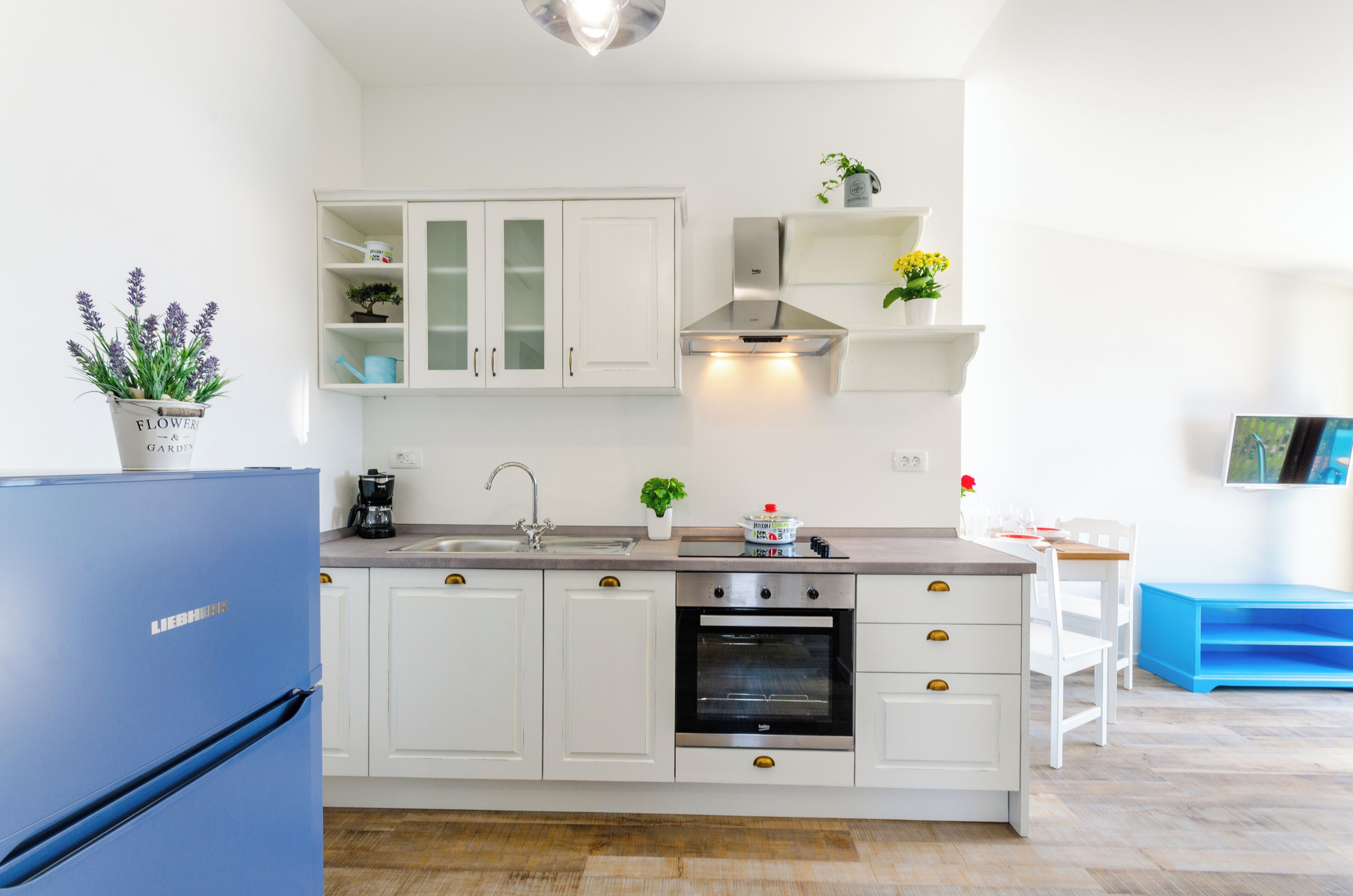 Eine moderne Küche mit weißen Schränken, einem eingebauten Ofen und einem blauen Kühlschrank.
