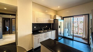 A modern kitchen with a black countertop, wooden cabinets, and a built-in refrigerator. - Stylish 2BR in L'Hivernage Pool & M'Avenue view (Marrakech)