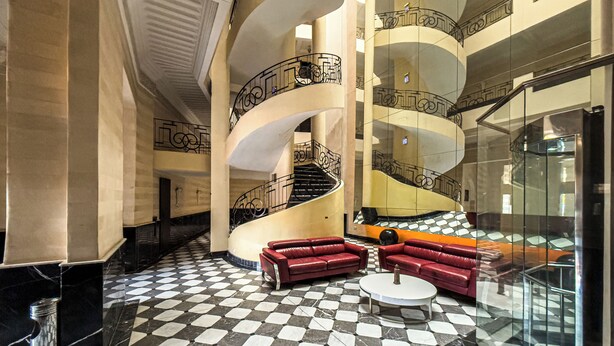 A lobby with a checkered floor, red sofas, a round table, and a spiral staircase. - Stylish 2BR in L'Hivernage Pool & M'Avenue view (Marrakech)