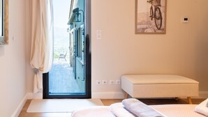 Une chambre d’hôtel avec une grande fenêtre, un banc et un tableau représentant un vélo, accroché au mur.