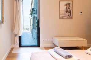 A hotel room with a large window, a bench, and a wall-mounted picture of a bicycle.