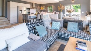 Une cuisine moderne avec des meubles blancs, un coin repas comprenant une table et des chaises, et un salon avec un canapé et une table basse.