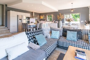 A modern kitchen with white cabinets, a dining area with a table and chairs, and a living room with a sofa and a coffee table.