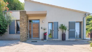 Une maison moderne à deux étages, dotée d’un pilier en pierre, d’une porte en bois et de volets.