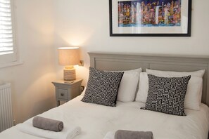 A neatly made bed with patterned pillows, a bedside lamp, and a framed picture on the wall. - Beautiful 4 bedroom House in a peaceful village  nr Rock & Port Gaverne (Saint Endellion)