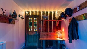 En smal hall med en träbänk, en dörr med målat glas och en vägghylla med diverse föremål.