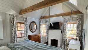 Une chambre à coucher comprenant un lit, une commode, un téléviseur, une cheminée et un bureau.