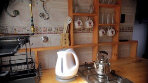 Una cocina con un hervidor, una estufa a gas y un recipiente para utensilios.