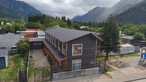 Un edificio de dos pisos con techo inclinado, un balcón y vistas a montañas.