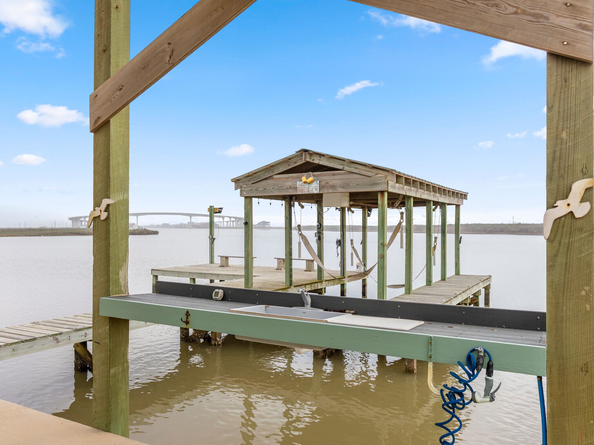 Un muelle de madera con un pabellón, un banco y una bomba de agua.