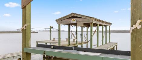 Un muelle de madera con un pabellón, un banco y una bomba de agua.