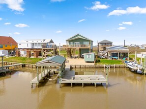 Ein Haus am Wasserufer mit Steg, einem kleinen Boot und einem Balkon.