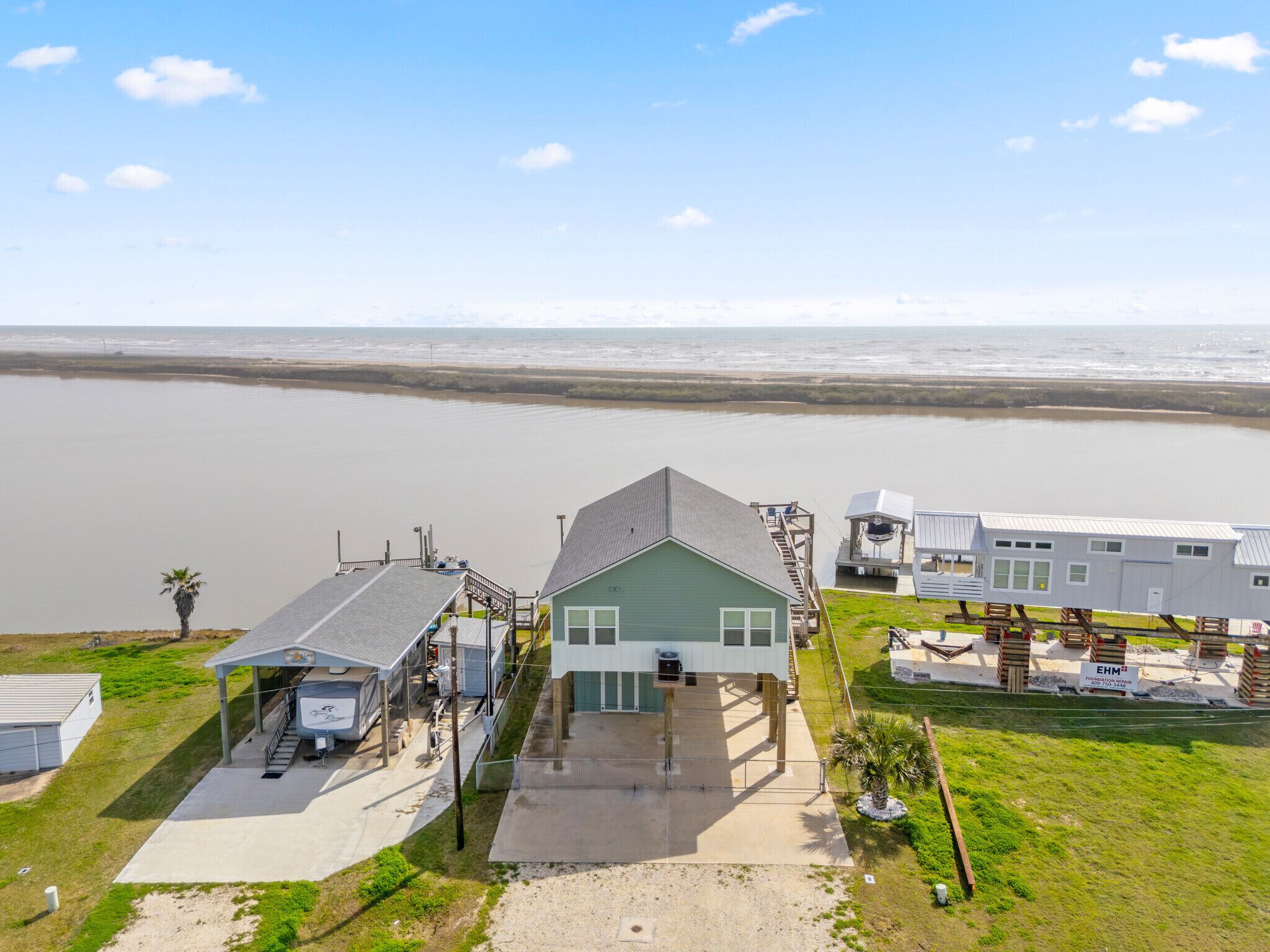A coastal property with a green house, a covered carport, and a trailer.