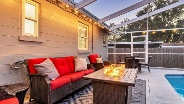 An outdoor patio with a sofa, table, and fire feature. - 3 BR Tampa Pool Home - Putting Green |Firepit |Coffee Bar (Tampa)