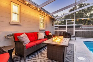 Eine Terrasse im Freien mit einer Couch, einem Tisch und einem Feuerkorb.