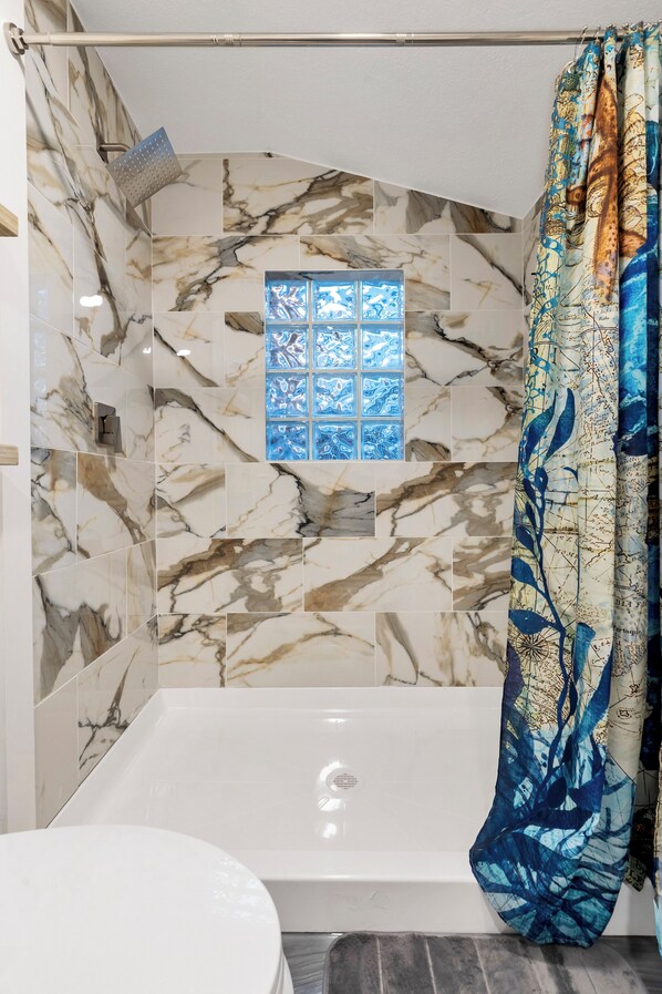 Un baño con ducha, ventana y bañera.