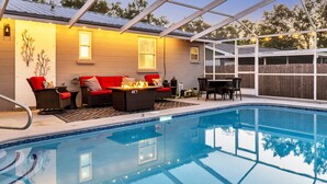 A covered outdoor pool area with a seating arrangement and a wooden fence in the background. - 3 BR Tampa Pool Home - Putting Green |Firepit |Coffee Bar (Tampa)