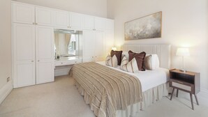 A bedroom with a bed, bedside table, dresser, mirror, and artwork on the wall. - Boutique Living in Iconic Mayfair (London)