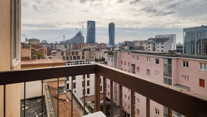 Paesaggio urbano con edifici moderni, un balcone e un cielo nuvoloso.