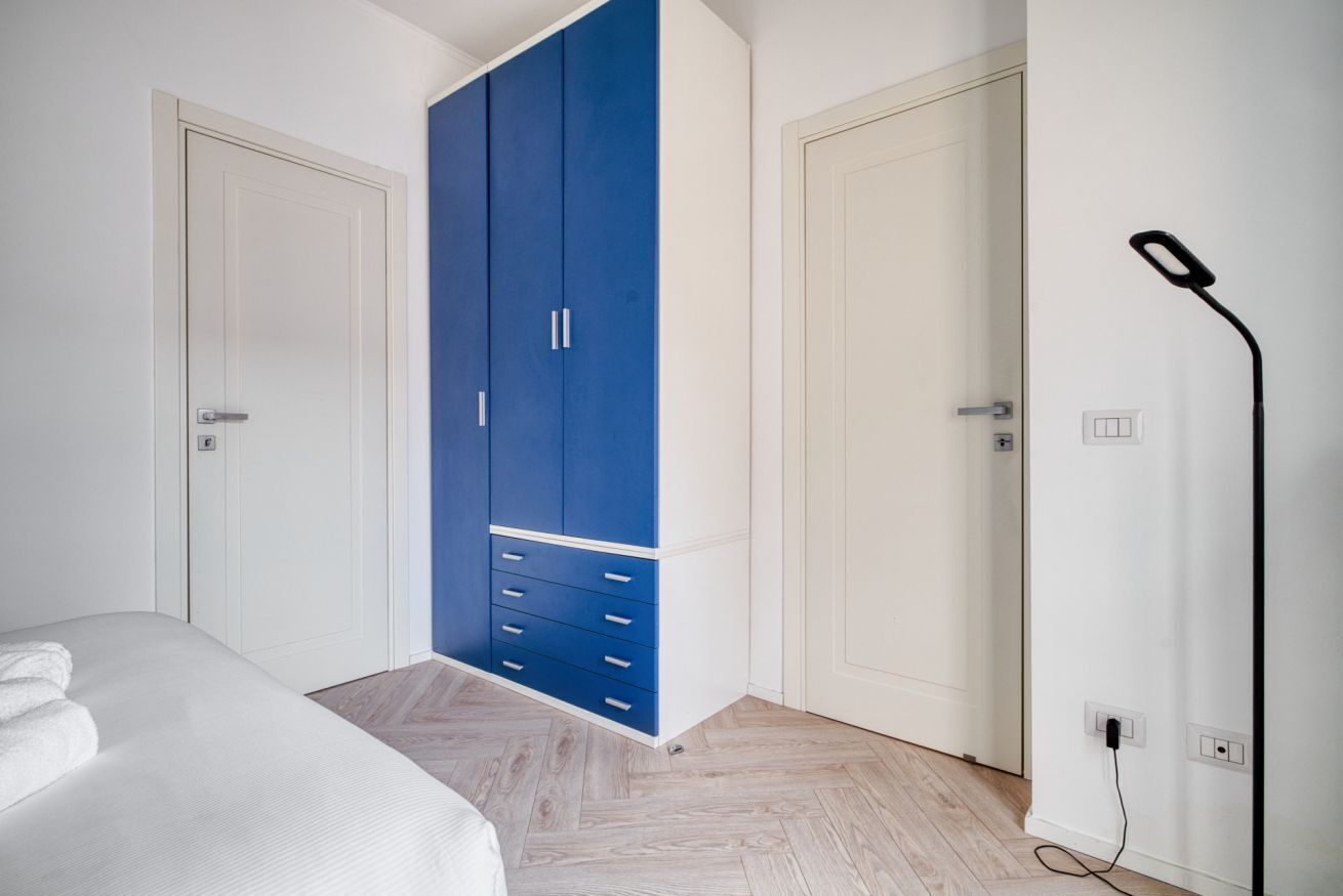 Ein Schlafzimmer mit einem Bett, einem blauen Kleiderschrank und einer weißen Tür.