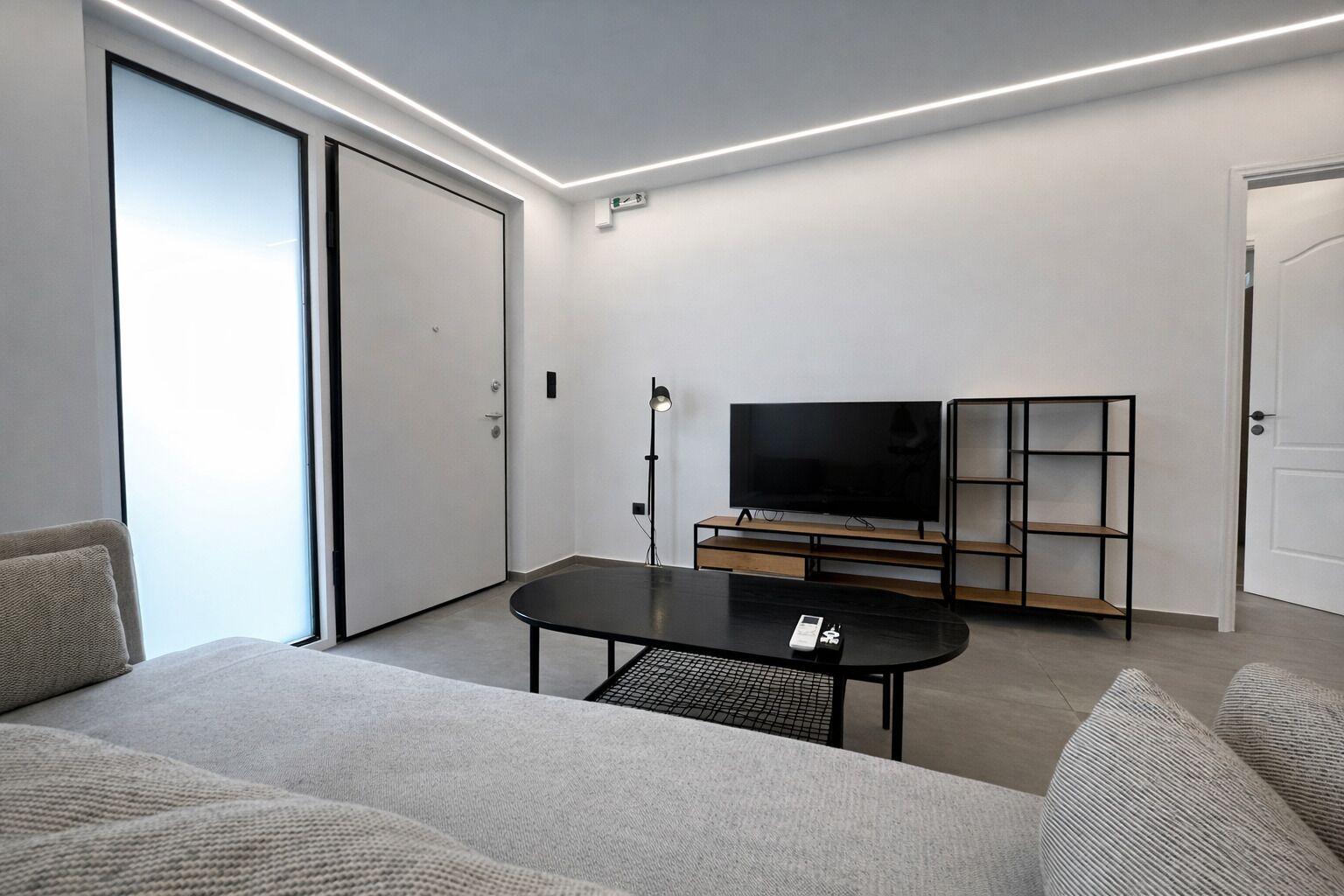 Un salon moderne avec un téléviseur à écran plat, une table basse et une bibliothèque.