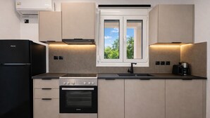 A modern kitchen with a built-in oven, a refrigerator, and a window with a view of greenery.
