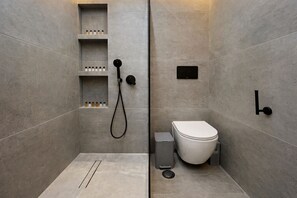 Un baño moderno con ducha, inodoro y estantes de almacenamiento.