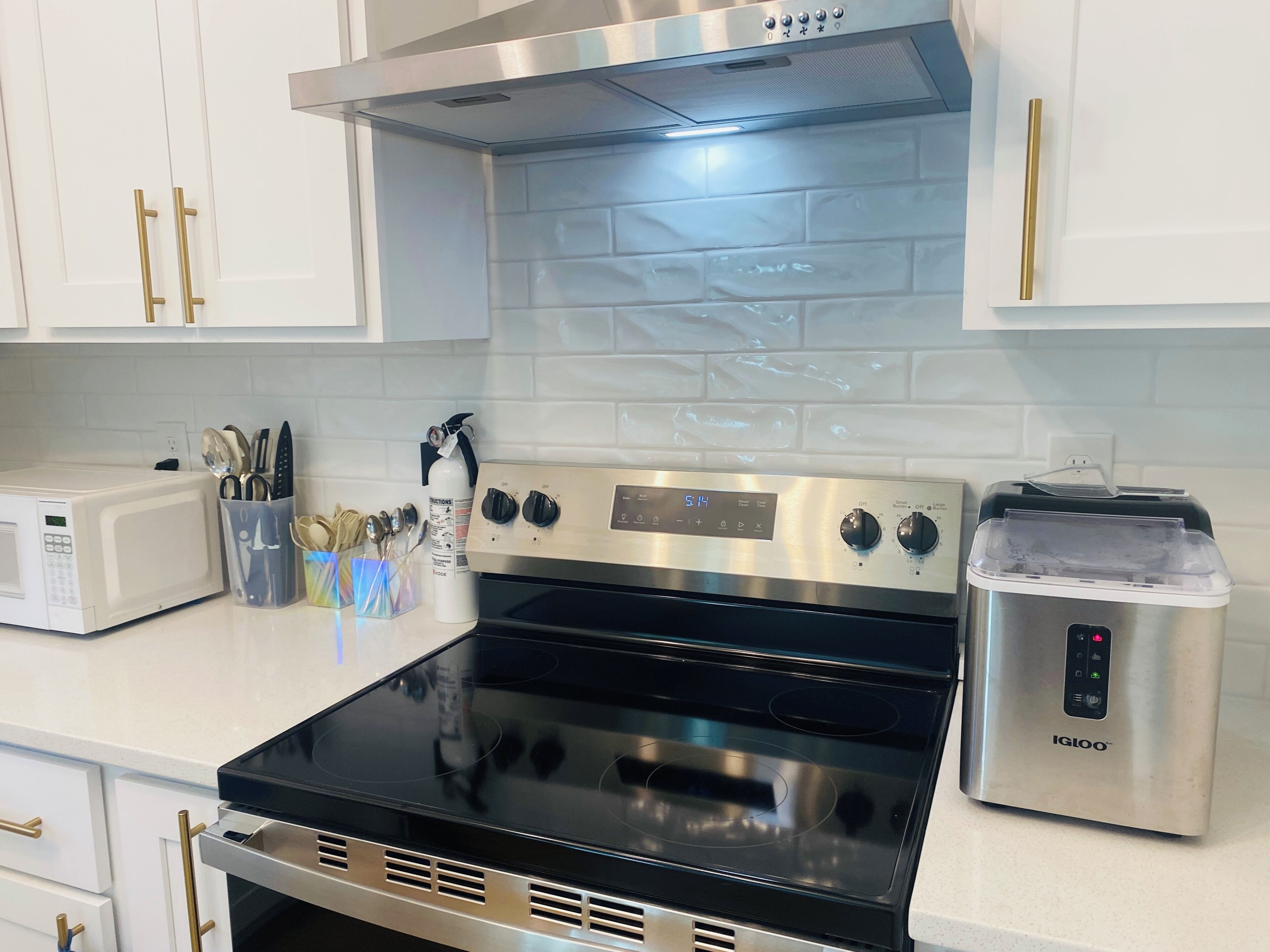 A kitchen with white cabinets, a microwave, a stainless steel stove, and a toaster.