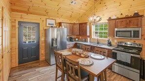 L’intérieur d’une cabane en bois comprend une cuisine, une table à manger, des chaises et un réfrigérateur.