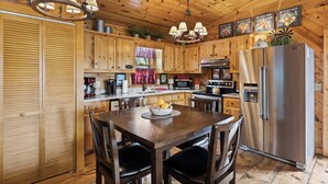 A wooden cabin kitchen with a central island, stainless steel appliances, and a chandelier. - Heart's Hideaway - Blue Ridge, GA (Morganton)