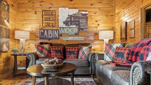 A cabin interior with a wooden interior, a sofa set, a round coffee table, and decorative pillows. - Heart's Hideaway - Blue Ridge, GA (Morganton)