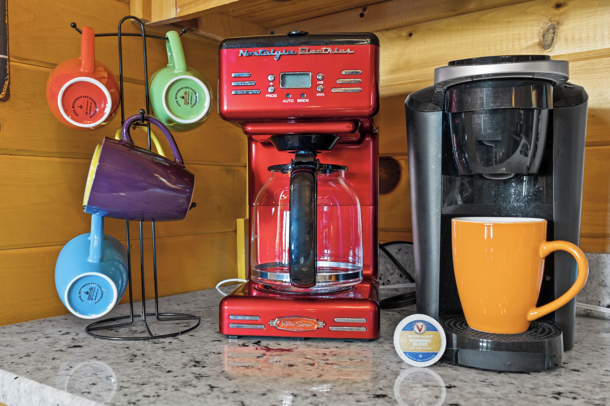 A coffee maker, a mug, and a cup on a kitchen counter.